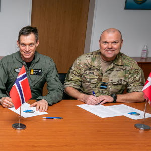 De nordiska flygvapencheferna sitter på rad vid ett bord framför sina flaggor. Alla klädda i militäruniform.
