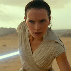 Närbild på Rey (Daisy Ridley) som stirrar rakt fram och har sitt lasersvärd redo bakom sig.
