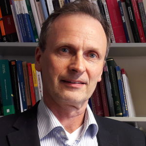 Kimmo Nuotio är professor i straffrätt vid Helsingfors universitet. Professor Kimmo Nuotio står framför en bokhylla.