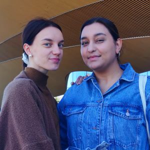 Emmi Hahto och Melissa Linsa står framför centrumbiblioteket Odes orangea fasad i Helsingfors,