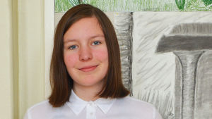 Maja Wickström En tonårsflicka står framför en vägg och tittar in i kameran.