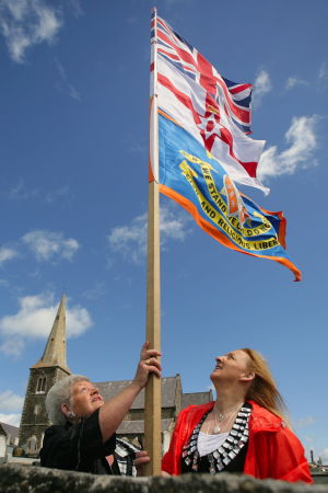 Två kvinnor hissar den brittiska och Oranieordens flagga inför paradsäongen i Nordirland