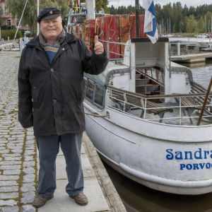 Skeppare Ari Kautto visar tummen upp där han står intill fartyget Sandra D.