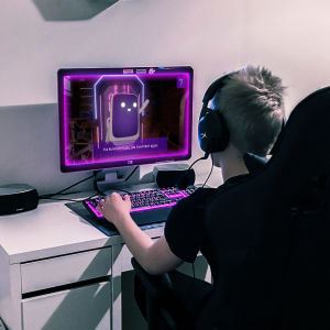 Poika pelaa tietokoneella Mysteerijuna-peliä kuulokkeet korvillaan