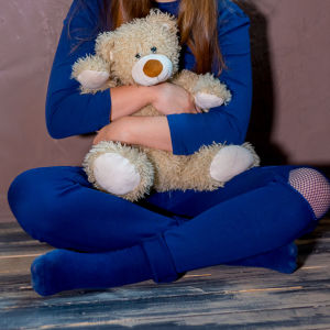 Ett barn med en teddybjörn i famnen. 