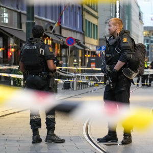 Två poliser i Norge står på en gata. I förgrunden polistejp.
