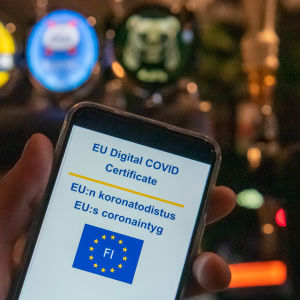 Digitalt covidintyg och telefon vid bardisk.