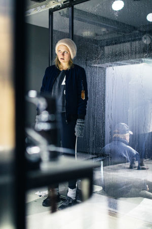 Ella Mettäsen näyttelemä Klara seisoo asunnossaan ja tarkkailee naapureitaan ikkunan läpi.