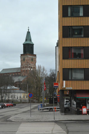 Åbo domkyrka kan ses vid korsningen av Universitetsgatan och Multavierugatan. Vy mot Åbo domkyrka, ett vitt och gult höghus står i förgrunden.