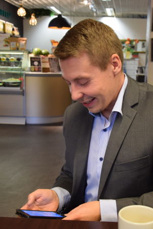 Barnombudsman Tuomas Kurttila tycker det är viktigt att vuxna engagerar sig i vad barnen gör på sociala medier. Barnombudsman Tuomas Kurttila på kafé med mobiltelefon i hand