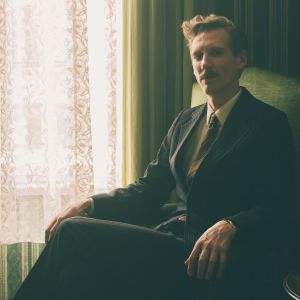 Touko Laaksonen (Pekka Strang) sitter i en fåtölj och ser rakt in i kameran.