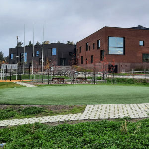 En stor brun tegelbyggnad vid en skolgård.