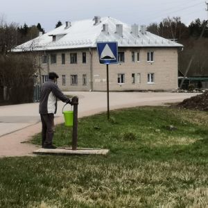 En man står vid en vattenpump i byn Torosjino