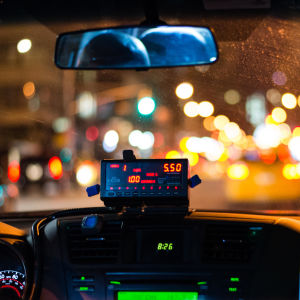 Förar- och passagerarsätet i en taxibil fotograferat från baksätet.