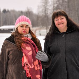 Två kvinnor i mörka vinterjackor poserar för kameran. Den ena ler, den andra ser mer orolig ut.