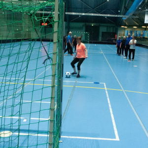 Seniorer tränar fotboll i en idrottshall
