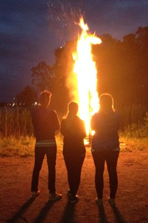Kristine Andora Nilsen, Elisabeth Gjestland och Jontti Granbacka betraktar midsommarbrasan på Fölisön