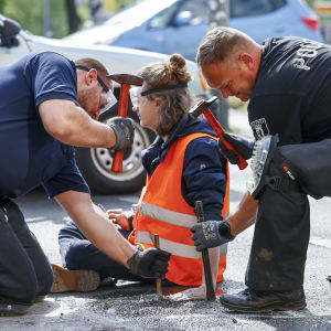 Polisen använder verktyg för att försöka få loss en Letzte Generation-aktivist som limmat fast sin hand på en bilvägi Berlin.