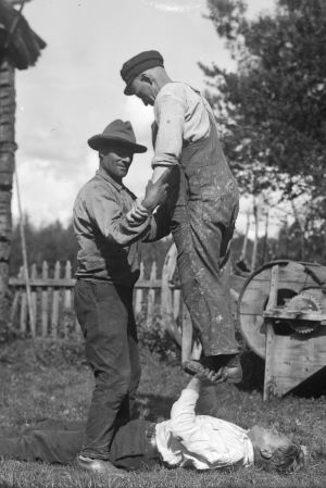 En man lyfter en annan man från hans skor med sina bara händer. Bilden är tagen 1932 i Terjärv.
