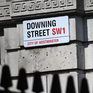 En gatuskylt på ett hörn där det står Downing Street SW1, City of Westminster.