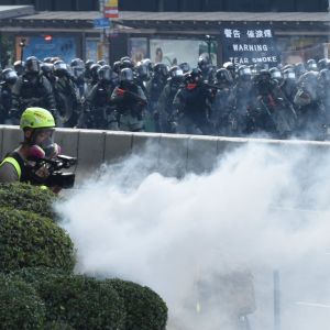 Kravallpoliser har skjutit tusentals tårgaskanistrar mot demonstranterna. Demonstranterna anklagar polisen för att ha gjort sig skyldig till kriminell brutalitet. Kravallpoliser skjuter tårgas mot demonstranter. Ett moln av rök och i bakgrunden en skylt med texten "Warning tear smoke". Polisen anklagas för kriminell brutalitet.