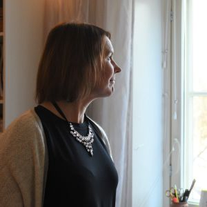 En kvinna tittar ut genom ett fönster.