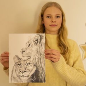 En ung tjej håller upp en teckning av två lejon, som hon själv har gjort.