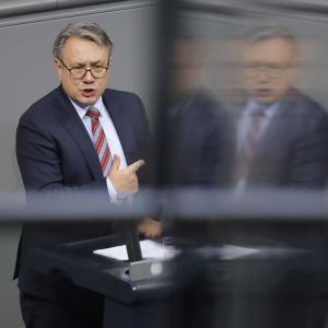CSU-politikern Georg Nüsslein ska ha tjänat hundratusentals euro på affärer med ansiktsskydd, samtidigt som många företag och privatpersoner står på konkursens brant på grund av coronakrisen. Den bayerske CSU-politikern Georg Nüsslein står och pratar och pekar i en talarstol. En suddig variant av honom speglas i en skärm.
