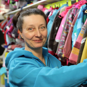 Kvinna står vid en hylla med en massa barnkläder.