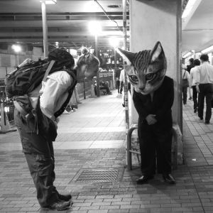 Nuori nainen ja kissapäinen mies tervehtivät toisiaan japanilaisella asemalla. Kuva elokuvasta Terveisiä Fukushimasta.