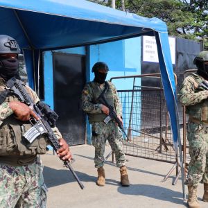 Tre poliser beväpnade med stormgevär vaktar ingången till fängelset Penitenciaría del Litoral i Guyaquil i Ecuador.