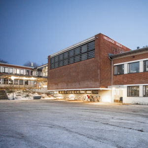 En skolbyggnad i rött tegel. På skolan står det "Helsinge skola". 