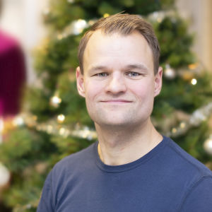 Peter Siegfrids i blå tröja framför en julgran.