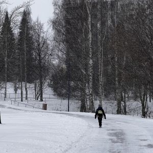 Person går genom en snöig park.