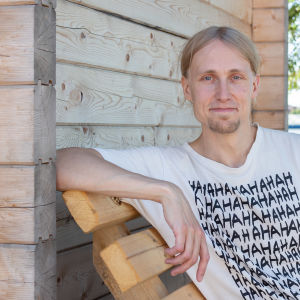Jaakko Blomberg istuu puisella penkillä saunarakennuksen vierustalla.