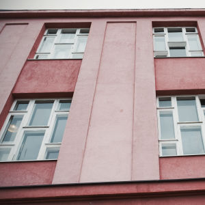 Vanha kerrostalo, kahdeksan ikkunaruutua joka ikkunassa, julkisivu vaaleanpunainen.