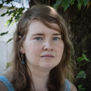 Porträttfoto av Mikaela Sallmén taget utomhus sommartid. 