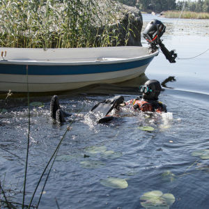 Dykare som sätter på grodfötterna i vattnet i en småbåtshamn