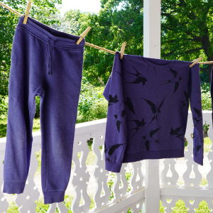 Kaksi housua ja yksi paita roikkuvat kuivumassa ulkona pyykkinarulla.