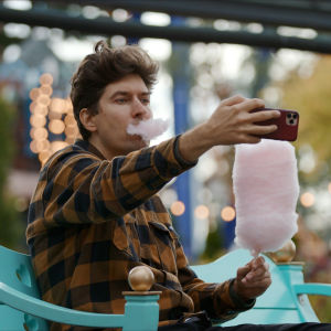 Kasper Strömman äter spunnetsocker och tar en selfie med sin telefon.