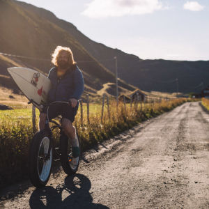 Twin bjuder på hisnande norska naturlandskap. Erik cyklar längs med naturskön sandväg med surfbräda under armen.