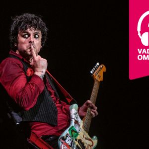 Billie Joe Armstrong står med ena pekfingret på munnen och med en elgitarr i famnen.