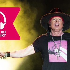 Axl Rose står med ena armen utsträckt åt sidan.
