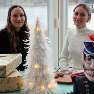 Pähkinänsärkijä-baletin fanit Emma ja Peppi Larjamo istuvat Kansallisoopperan lämpiössä. Kuvan etualalla Pähkinänsärkijä-nukke, jota käytetään myös esityksessä.