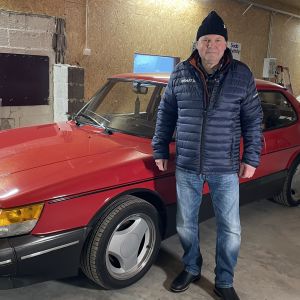 En man står i ett garage. Bredvid sig har han en röd Saab Turbo.
