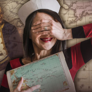Nainen merimieslakki päässään pitää toista kättä silmillään ja toisessa kädessä karttaa. Taustalla James Cook ja maailmankarttaa.