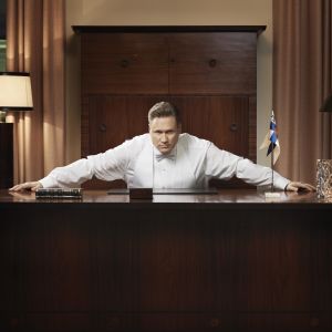 Pöydän äärellä vakavana istuu Samuli Edelmann, hän on roolissaan Henri Talviona sarjassa Presidentti.