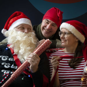 Kike är utklädd till jultomten som delar ut gåvor till Jens och Jenny prydda i tomteluvor.