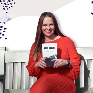 Kirjailija Satu Rämö pitää käsissään kirjaansa Hildur. Taustalla graafinen taustakuva.