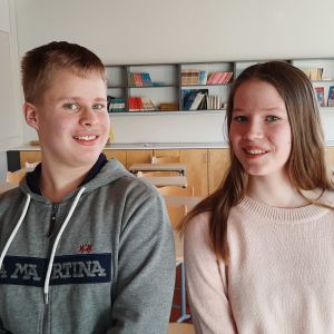 Johan Santalahti och Alexandra Jensen, två ungdomar sitter på en pulpet i ett klassrum.